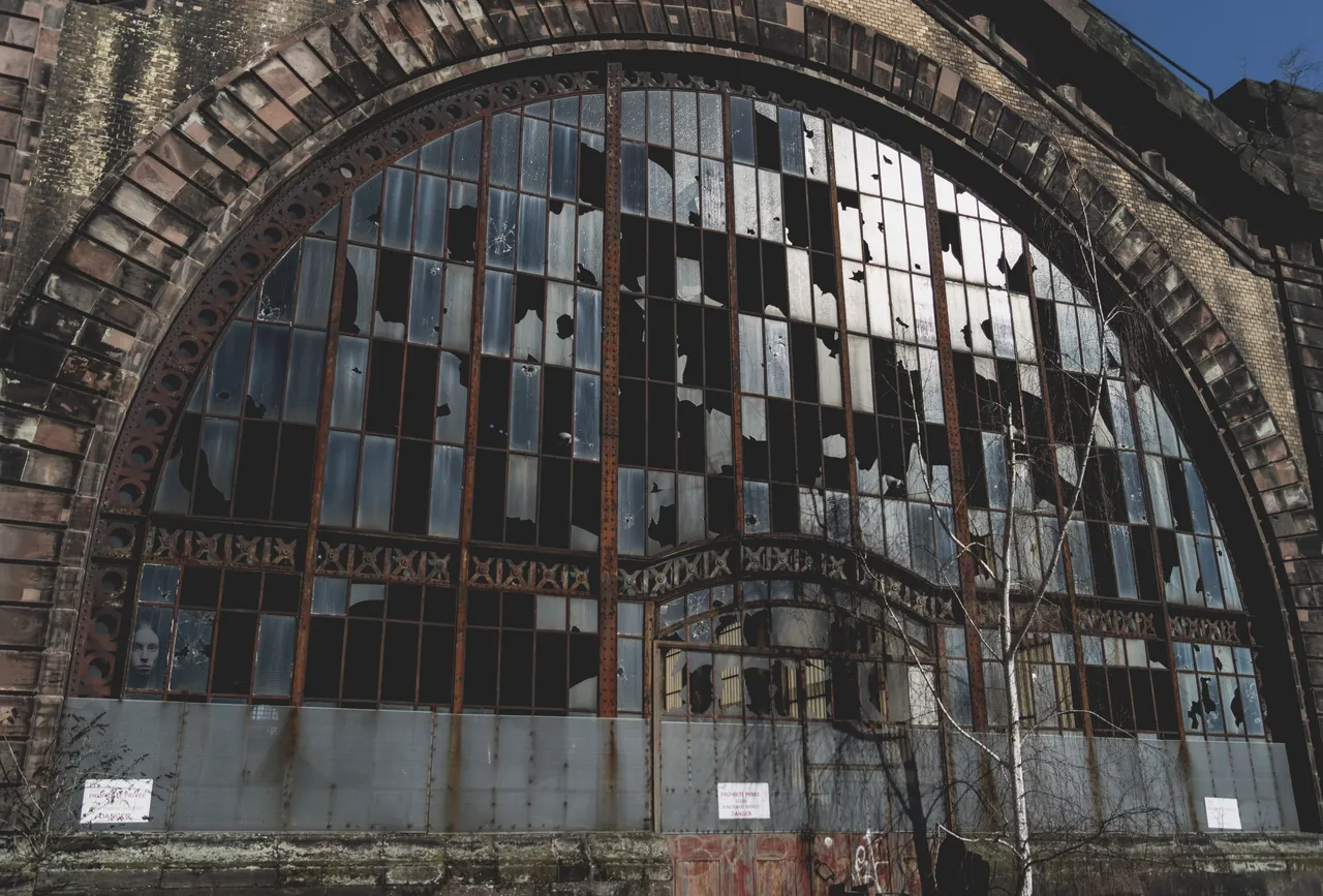 Abandoned industrial hall with a broken arched window